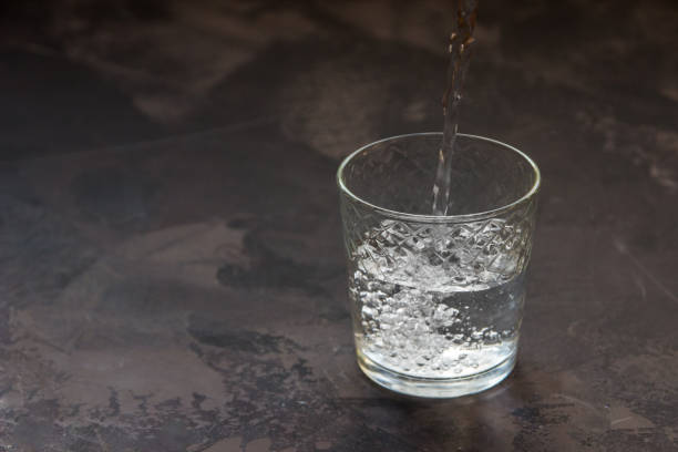 istock Water pouring into a glass, dark background 915319856