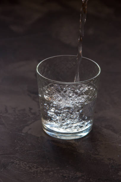 istock Water pouring into a glass, dark background 915319886