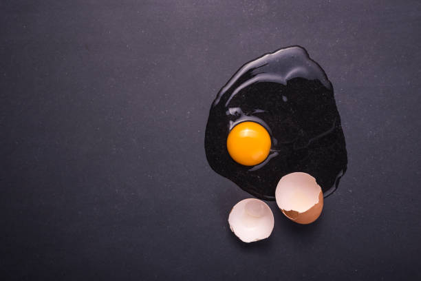 istock Broken eggs on the black stone ground. Free space for text and design. Top view 915321394