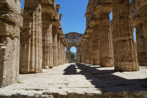 Temples of Paestum, Italy view inside, way with massive columns on both sides, wide-angle, deep blue sky, sunlight