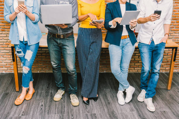 gruppo di uomini d'affari asiatici e multietnici con abito casual che utilizzano la tecnologia mobile, tablet, laptop e computer per lavorare o social network nel moderno office, concetto di gruppo aziendale per persone - smart casual foto e immagini stock