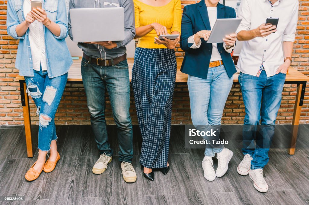 Group Of Asian and Multiethnic Business people with casual suit using the technology mobile, tablet, laptop and computer for working or social network in modern Office,people business group concept Office Stock Photo