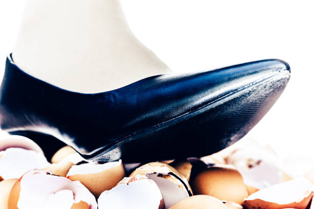 Walking on eggshells Walking on eggshells metaphor showing close-up of female human lower leg above broken eggshells. animal egg walking on eggshells walking broken stock pictures, royalty-free photos & images