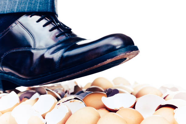 Walking on eggshells Walking on eggshells metaphor showing close-up of male human lower leg above broken eggshells. animal egg walking on eggshells walking broken stock pictures, royalty-free photos & images