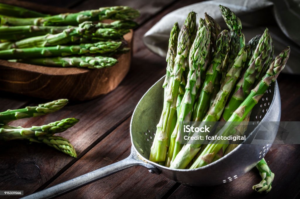 Fresh asparagus in an old metal colander Fresh organic asparagus in an old metal colander shot on rustic wooden table. This vegetable is considered a healthy salad ingredient. Predominant colors are green and brown. Low key DSRL studio photo taken with Canon EOS 5D Mk II and Canon EF 100mm f/2.8L Macro IS USM Asparagus Stock Photo