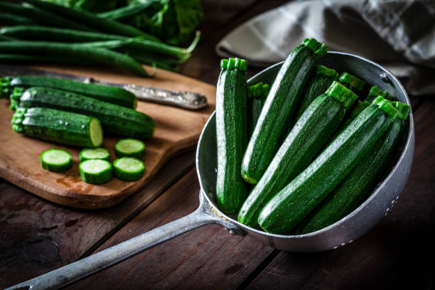 zucchine in un vecchio colino metallico - zuchinni foto e immagini stock