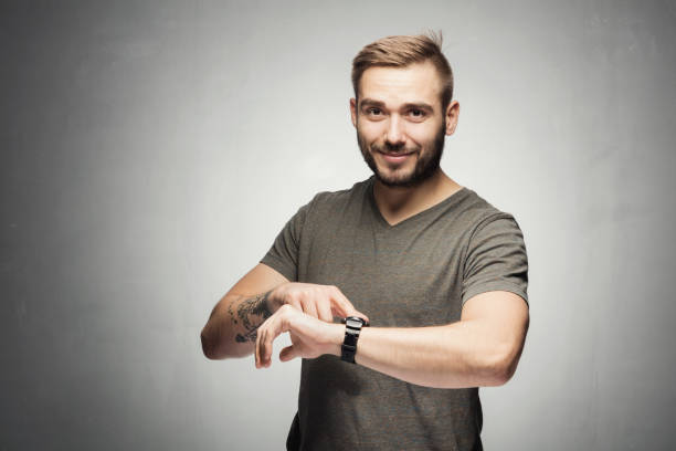 Handsome man pointing at a watch on the wrist. It's time concept