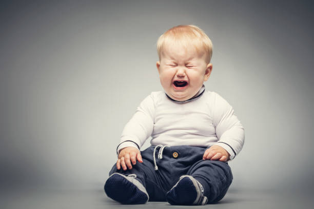 Crying baby sitting on the ground. Little baby boy sitting on the ground with crying face expression. crying stock pictures, royalty-free photos & images