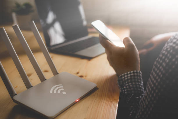 closeup de un router inalámbrico y un hombre con smartphone en sala de estar del hogar ofiice - wireless technology fotografías e imágenes de stock