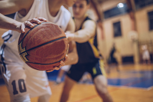 Basketball player in red jersey trying to block opposite team player with ball during match.