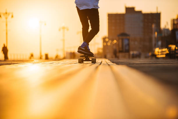 junger mann reiten longboard auf den bordwalk füße nur - longboard skating stock-fotos und bilder