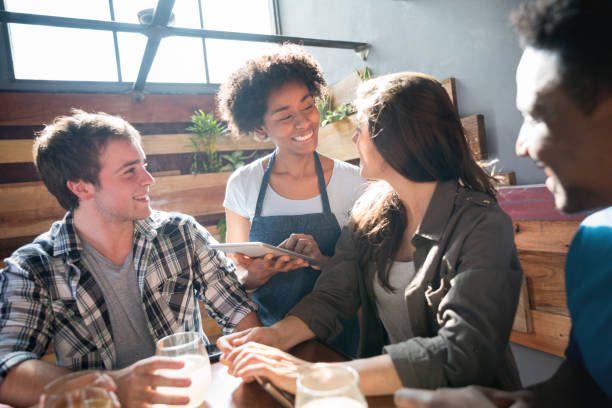 istock African american waitress taking an order on a computer tablet from a female customer 915352864