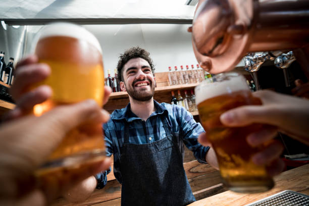 Friendly bar tender handing out tap beer to unrecognizable customers