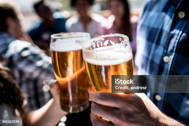 Close Up Of A Customers At A Bar Holding A Beer And Making A Toast Stock Photo - Download Image Now