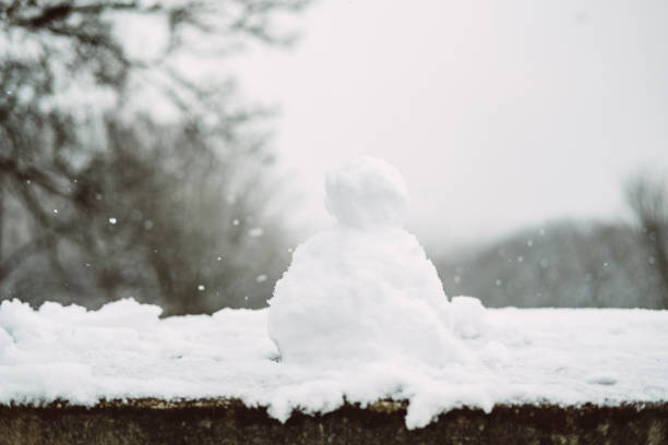 istock Mini Snowman on a wall on a snowy Winters day. 915362452