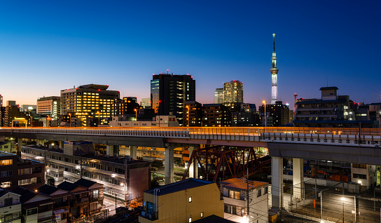 A sunset in Koto City area of Tokyo, Japan. Skytree tower is visible in the distance with a highway in the foreground.