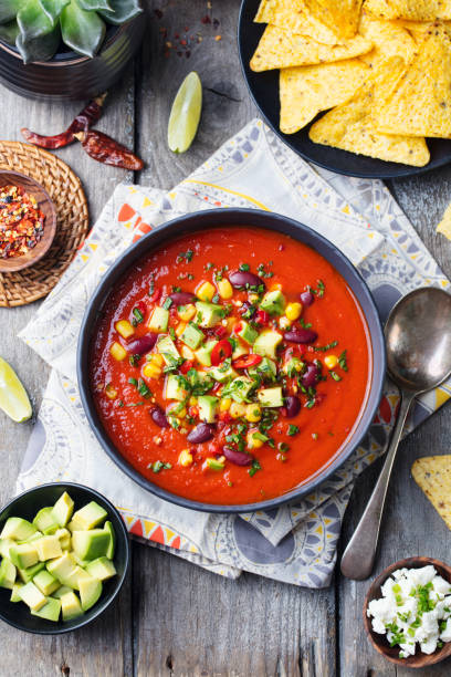istock Mexican tomato, bean, bell pepper soup in black bowl. Top view 915372930