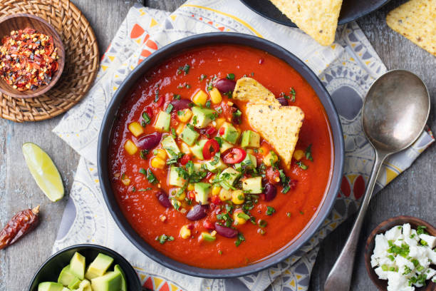 istock Mexican tomato, bean, bell pepper soup in black bowl. Top view 915373064
