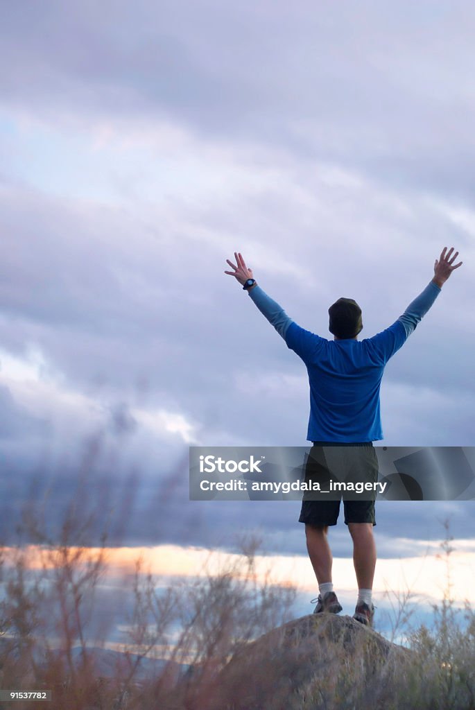 Człowiek stojący z Podniesione ramiona o w zmierzchu niebo - Zbiór zdjęć royalty-free (Chmura)