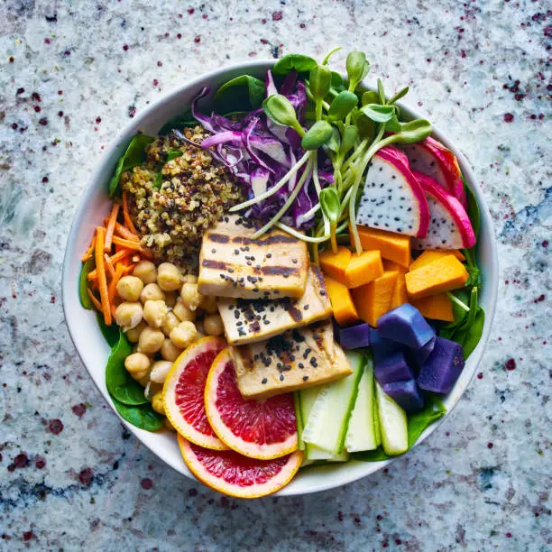 colorful buddha bowl with grilled tofu and dragon fruit, , bowl has blood orange, sweet potato, pea shoots and chickpeas