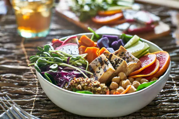 colorful buddha bowl with grilled tofu and pea shoots shot with selective focus