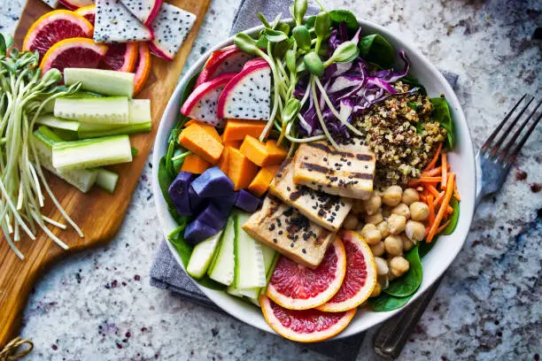 colorful buddha bowl with grilled tofu and dragon fruit shot top down on marble table top