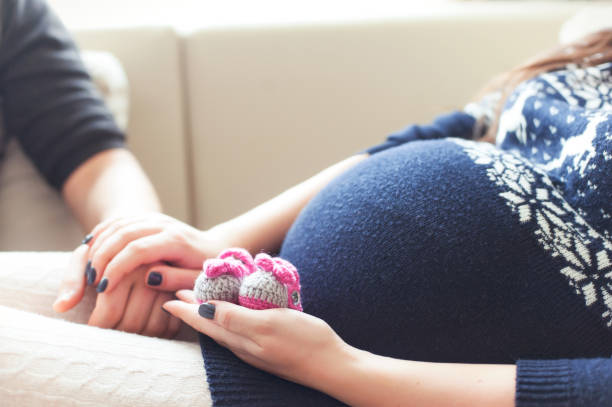 Happy future pregnant woman hands holding knitted newborn baby booties Young happy pregnant woman hands holding woollen knitted newborn baby booties. Indoors horizontal colored close-up image with soft vintage filter. cute pregnant woman with gift stock pictures, royalty-free photos & images