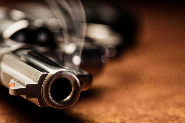 Smoking gun lying down on the floor A close-up of a chrome .357 magnum revolver hand gun smoking lying on the floor after being shot, with smoke rising from the end of the barrel. gun barrel stock pictures, royalty-free photos & images
