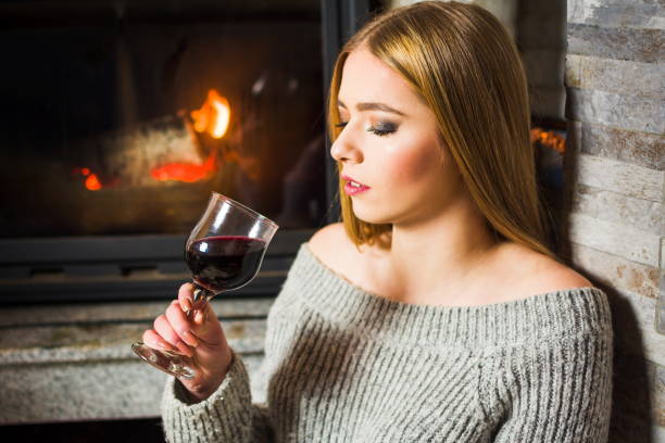 istock Girl drinking wine by the fireplace 915400034