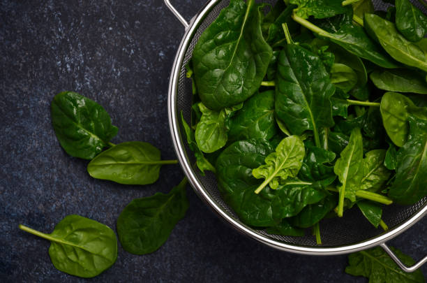 istock Fresh green spinach leaves on a dark concrete background. 915402748
