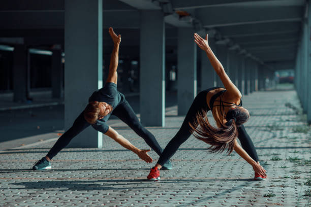istock Young couple warming up in urban environment before jogging 915404354