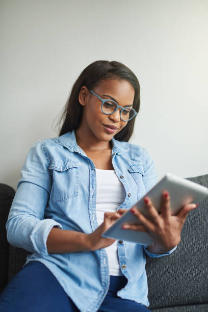 istock Smiling African woman relaxing on her sofa with a tablet 915413860