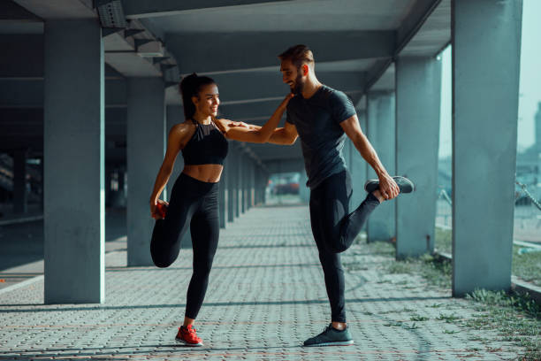 istock Young couple stretching legs in urban environment 915425764