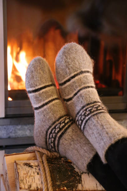 istock Feet in wool socks warming at the fireplace 915444626