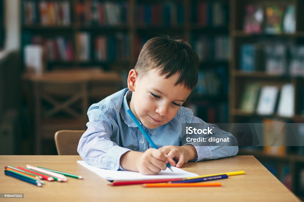 Preschool boy drawing Cute  boy doing homework,  coloring pages, writing and painting. Children paint. Kids draw. Preschooler with books at home. Preschoolers learn to write and read. Creative boy. Child Stock Photo