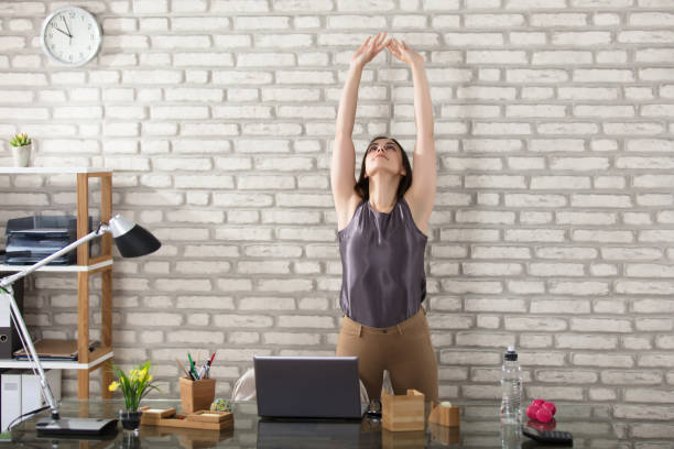 femme d’affaires qui s’étend - yoga business women indoors photos et images de collection