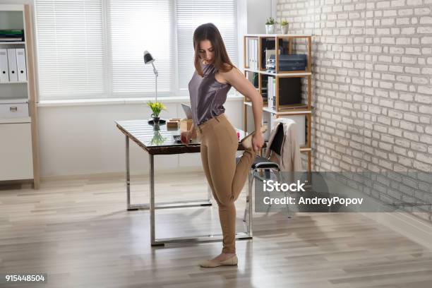 Businesswoman Stretching Her Leg In Office Stock Photo - Download Image Now - Exercising, Office, Resting