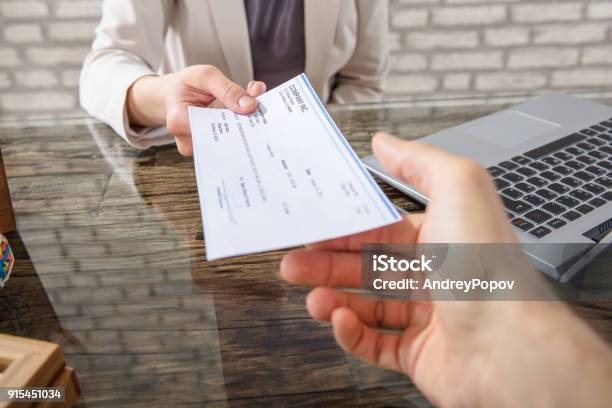 Businesswoman Giving Cheque To Her Colleague Stock Photo - Download Image Now - Check - Financial Item, Wages, Paying