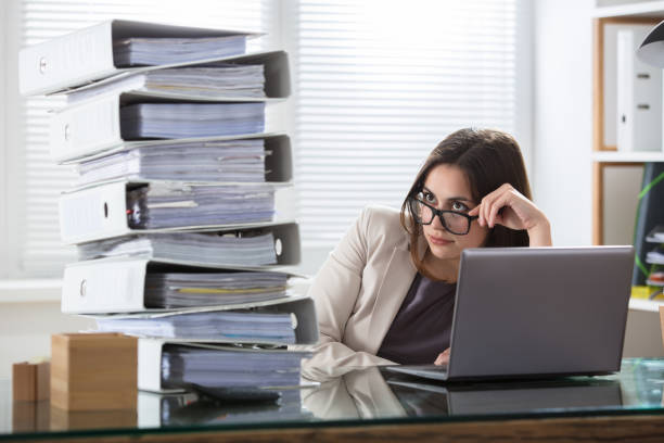 istock Worried Businesswoman Looking At Folders Stack 915451276