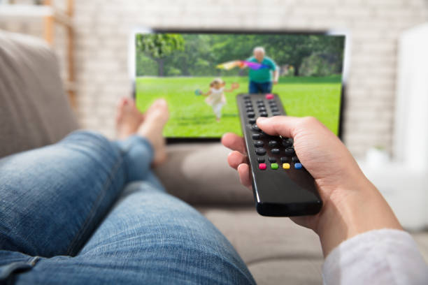 istock Woman Changing The Channel With Remote Control 915452016