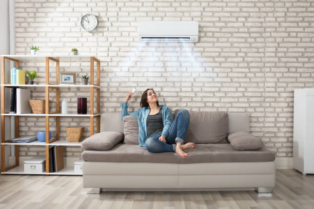 Woman Relaxing Under The Air Conditioner Happy Young Woman Holding Remote Control Relaxing Under The Air Conditioner adjusting seat stock pictures, royalty-free photos & images