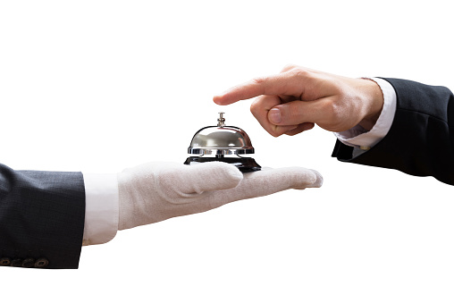 Close-up Of Person's Hand Ringing Service Bell Held By Waiter On White Background