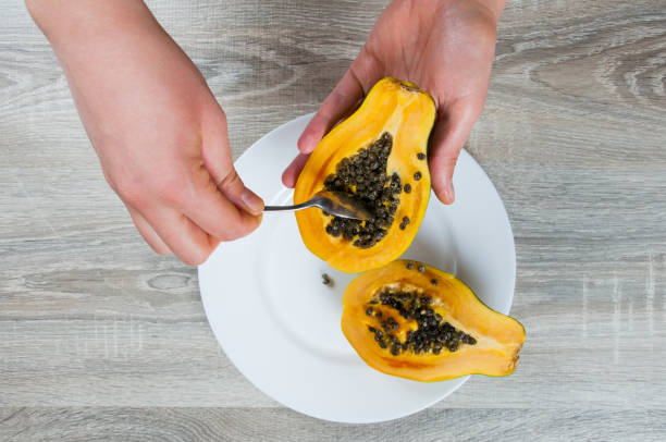 istock Closeup on hand holding ripe half papaya on table background 915461162