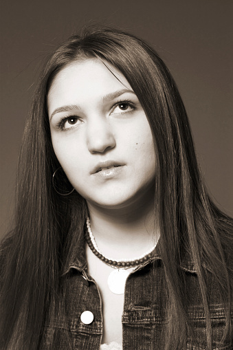 sepia toned image of a teenage girl thinking