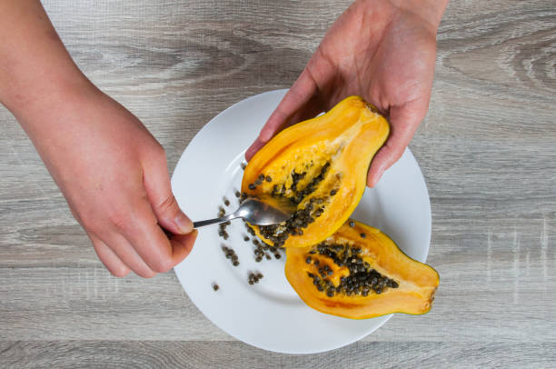 istock Closeup on hand holding ripe half papaya on table background 915461318