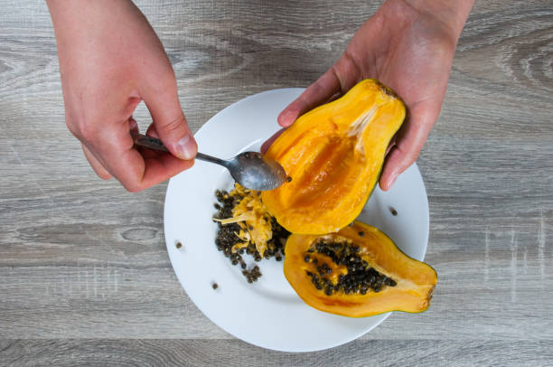 istock Closeup on hand holding ripe half papaya on table background 915461430