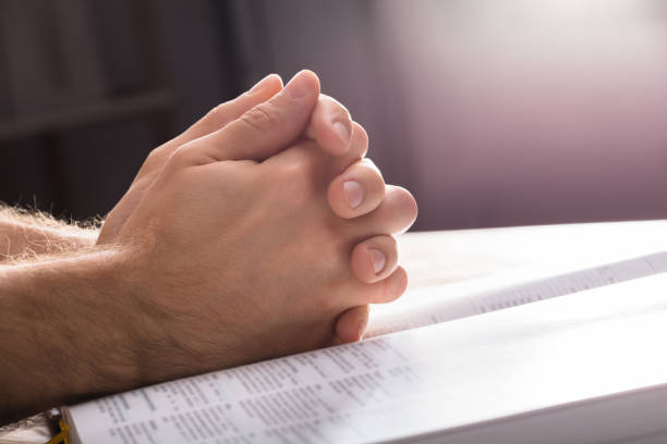 Praying Hands Over The Bible Close-up Of Man's Praying Hands Over The Bible apostle worshipper photos stock pictures, royalty-free photos & images