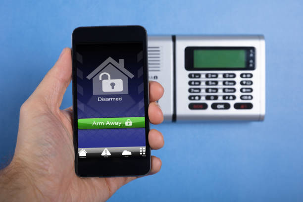 istock Hand Holding Smartphone For Arming The System 915461760
