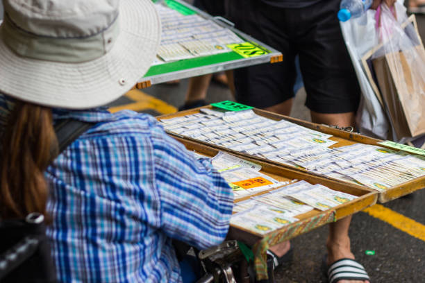 Girls sit the wheelchair and sell government's lottery at a street market stock photo