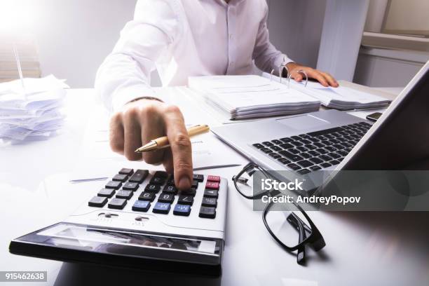 Businessman Calculating Tax Using Calculator Stock Photo - Download Image Now - Accountancy, Tax, Financial Advisor